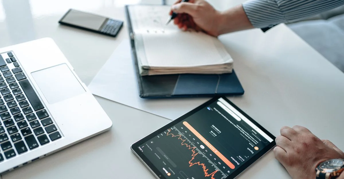 Gros plan d'un professionnel analysant les tendances de données à l'aide d'une tablette et d'un ordinateur portable.