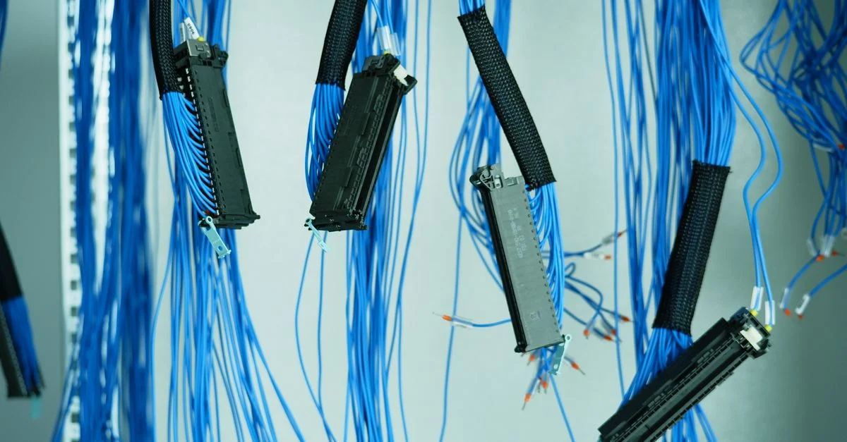Gros plan sur des câbles ethernet bleus suspendus dans un centre de données, mettant en avant les connexions technologiques.