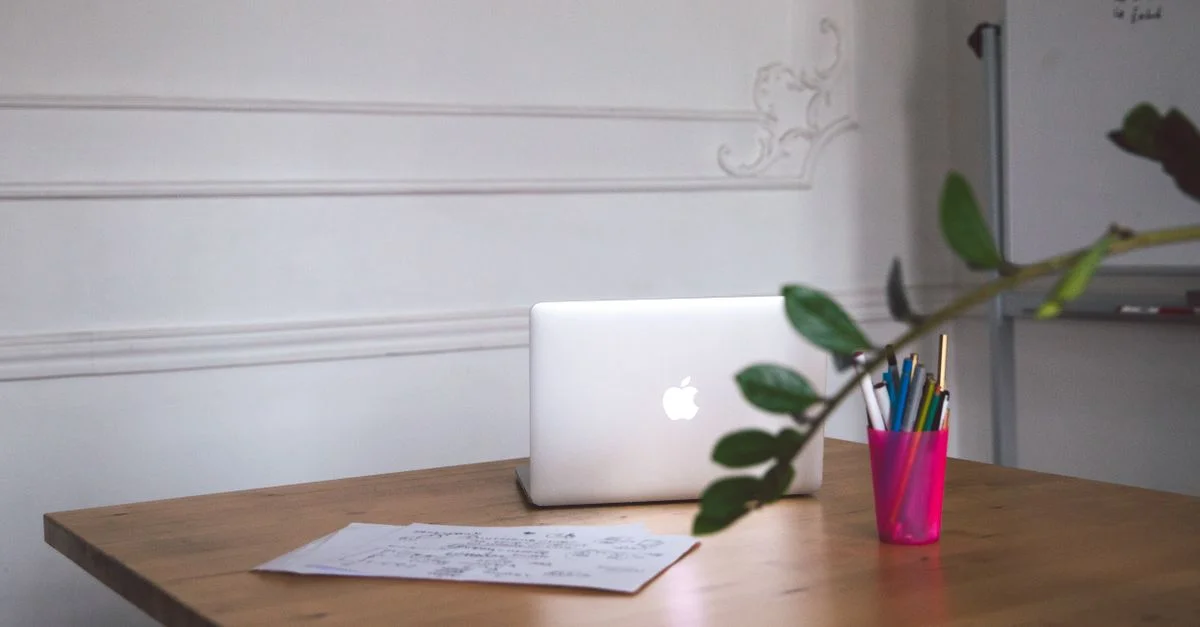 Un bureau propre avec un ordinateur portable, des notes et des stylos créant un espace de travail moderne.