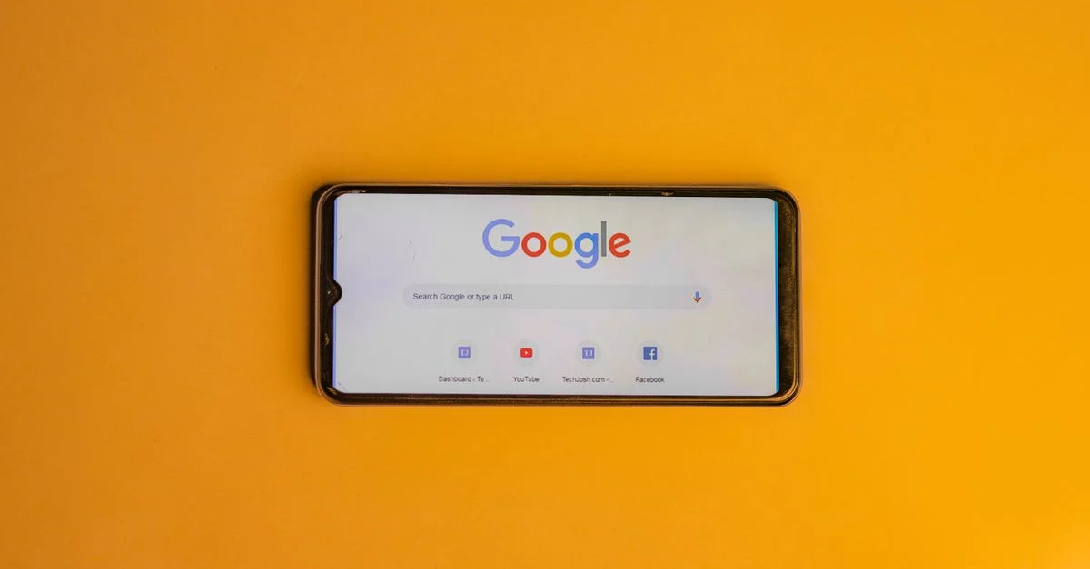Smartphone affichant la page de recherche Google sur un fond jaune vif.