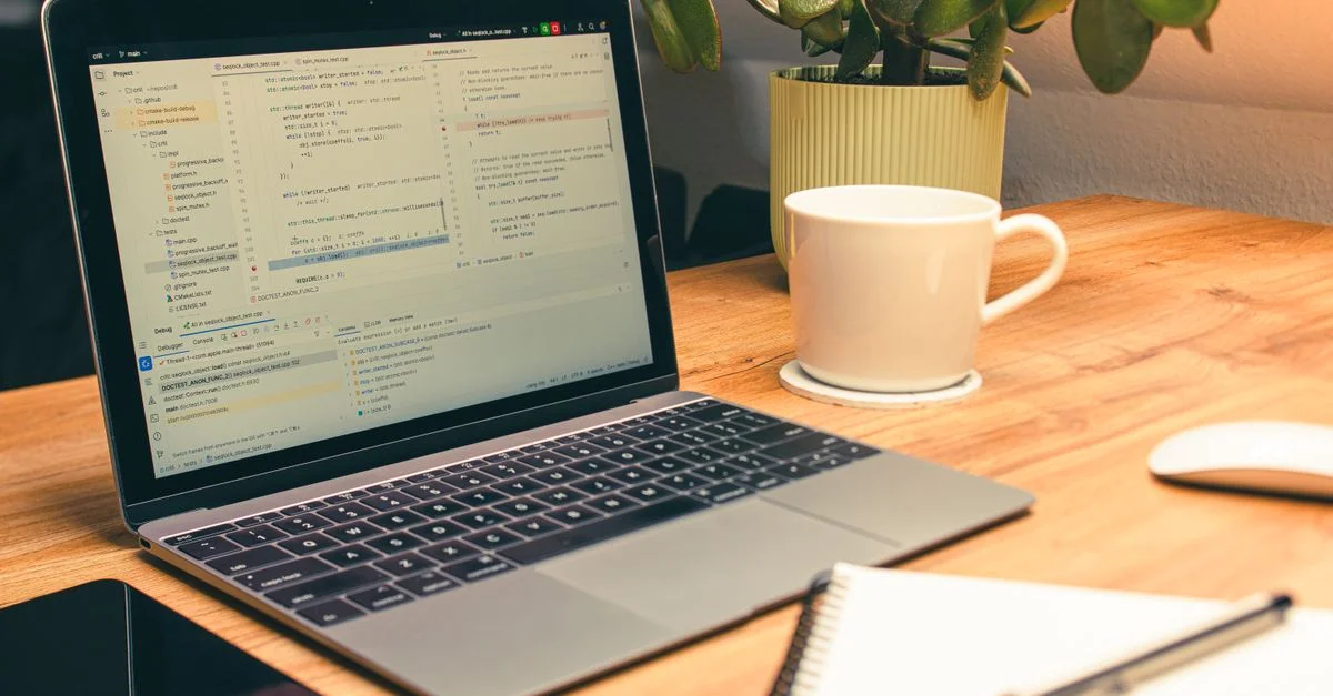 Espace de bureau confortable à domicile avec un ordinateur portable, du café et une plante verte pour la productivité.