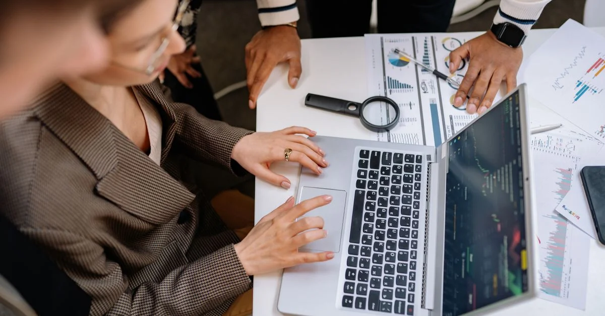 Des professionnels d'entreprise analysant des données sur un ordinateur portable, travaillant sur des stratégies de projet à la table de bureau.